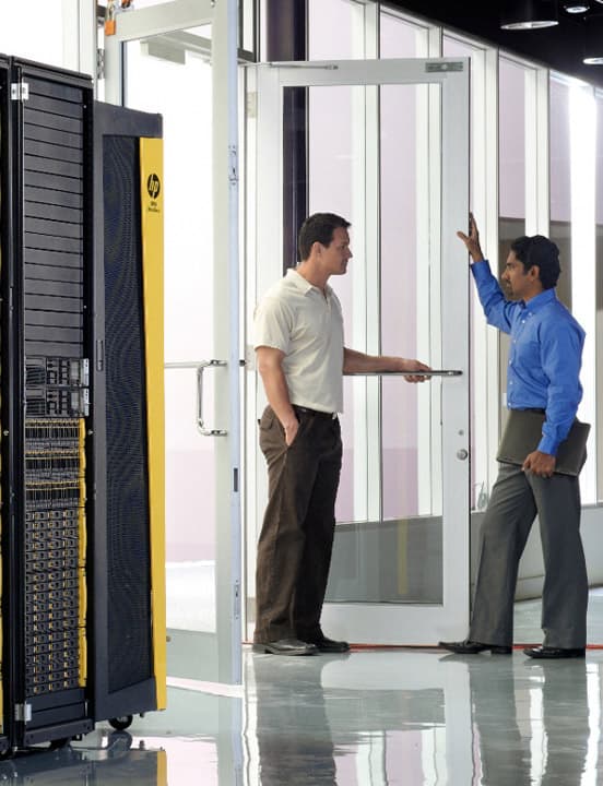 two men standing near HPE server rack