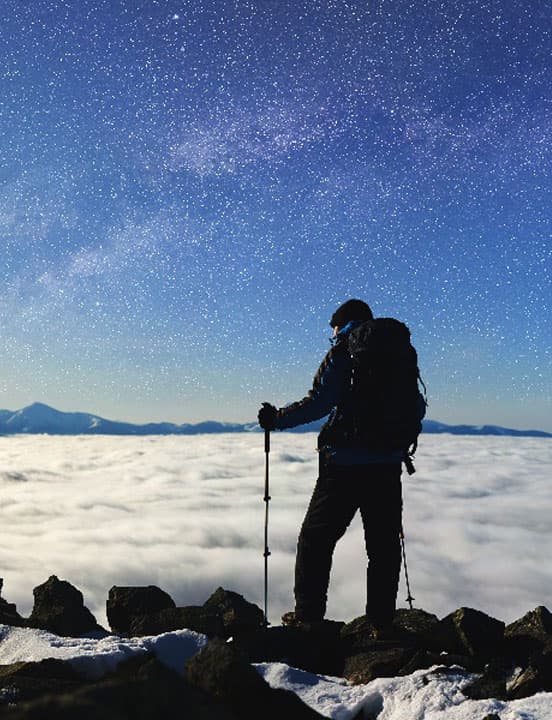 person looking at stars above cloud line