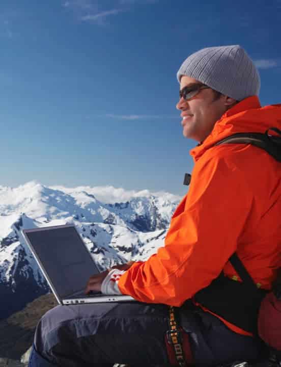 man with computer on top of a mountain