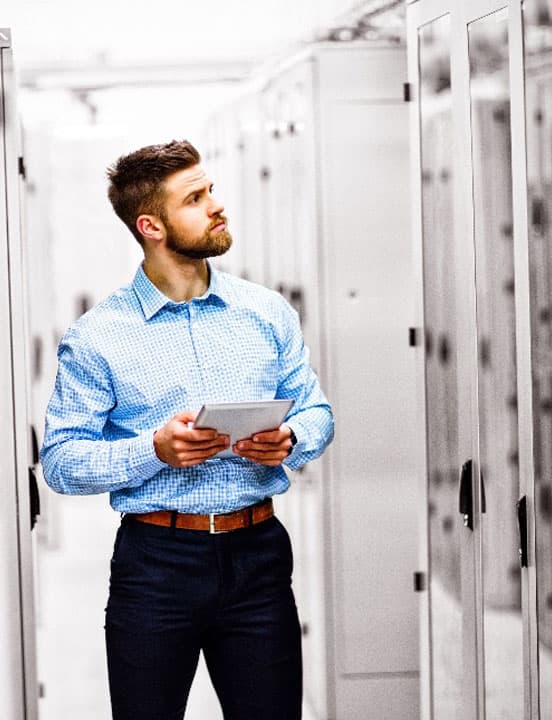 man looking into cabinets at data center