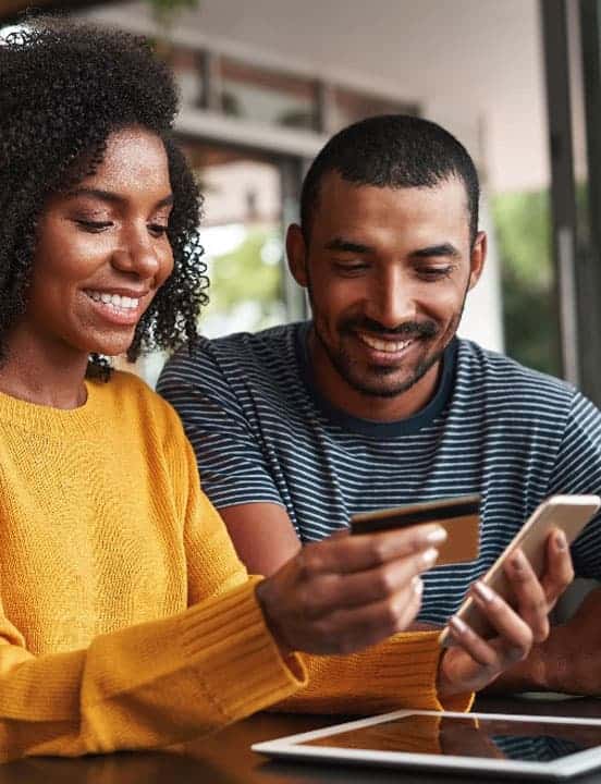 Couple holding credit card looking at phone