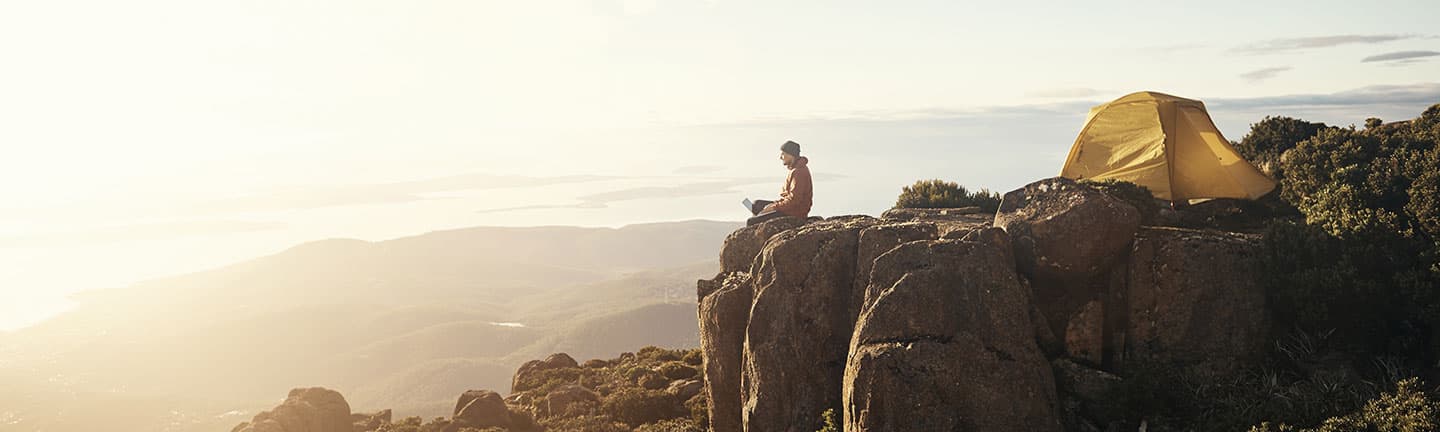 Man sitting on cliff with computer using citrix