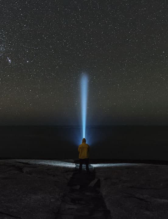 person holding light to the night sky