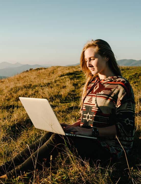 woman on hilltop looking at laptop