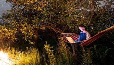 person sitting in hammock with laptop