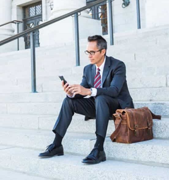 man sitting on steps of government building looking at phone