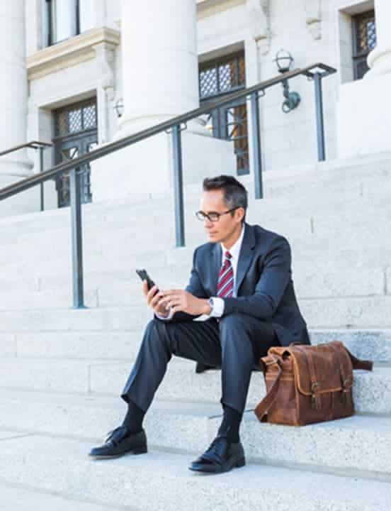 man sitting on steps of government building looking at phone