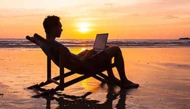 man using laptop on the beach
