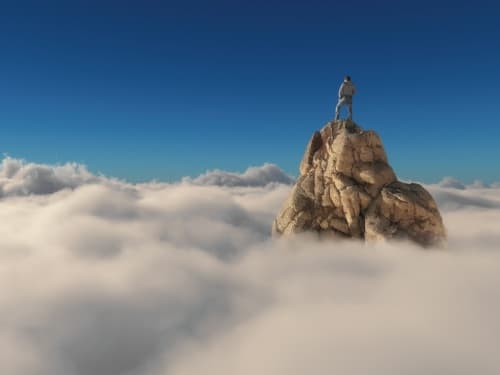 A man on a rock above the cloud line