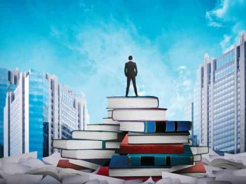 small man standing on large books