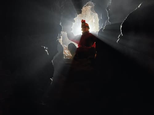 person in cave with light shining behind them