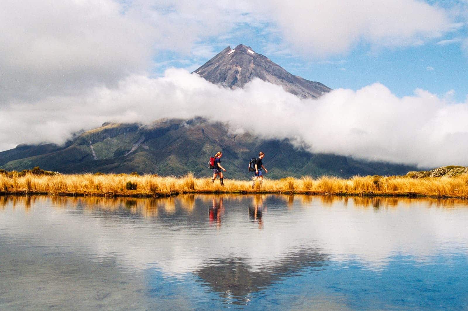 Hikers Reflection of Mount Taranaki Egmont in natural lake middle