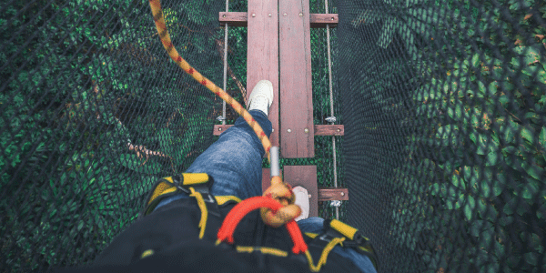 person walking on rope course bridge