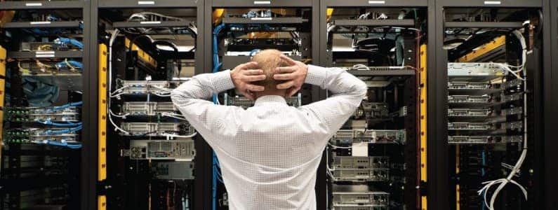 frustrated man in front of server racks frustrated man in front of server racks